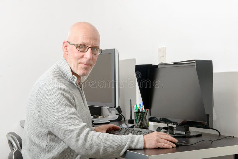 Mogen man som arbetar med hans dator arkivbild Mogen man som arbetar med hans dator arkivbild