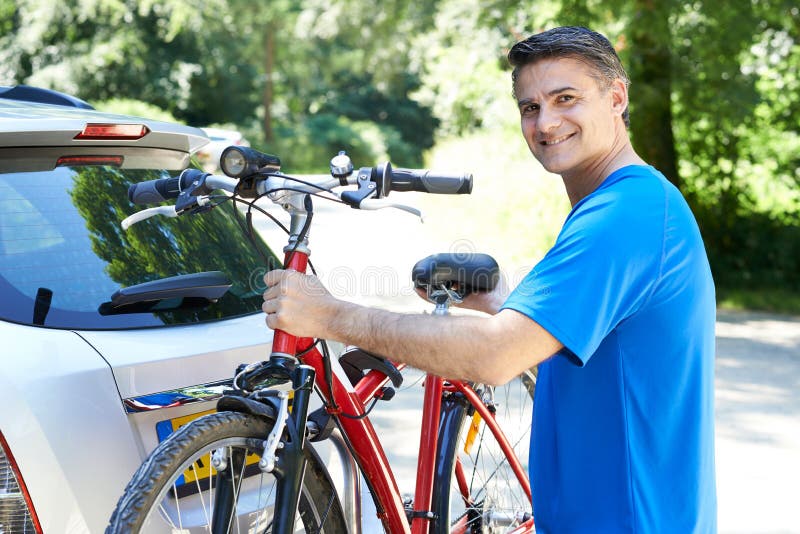 Mogen manlig cyklist som tar mountainbiket från kuggen på bilen arkivfoto Mogen manlig cyklist som tar mountainbiket från kuggen på bilen arkivfoto