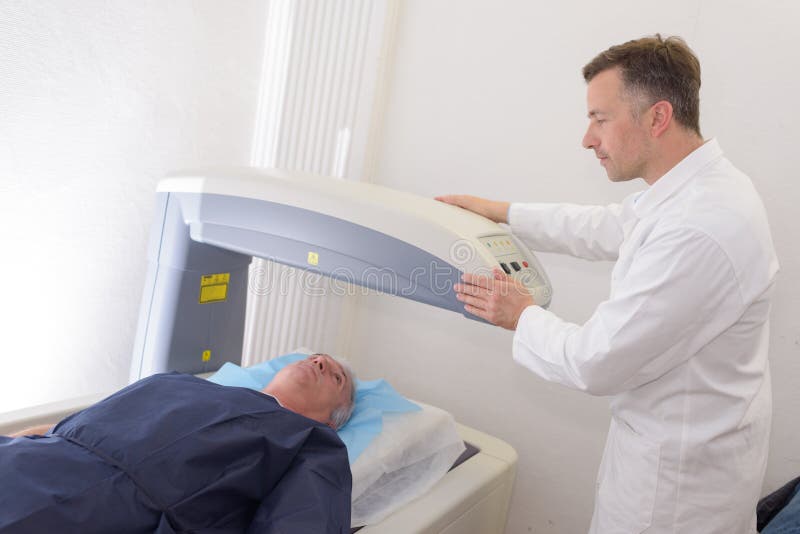 Radiologic technician mature male patient lying on scan bed xray. Radiologic technician mature male patient lying on scan bed xray