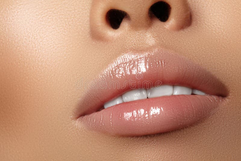 Moisturizing lip balm, lipstick. Close-up beautiful wet lips. Full lips with gloss lip makeup. Filler Injections