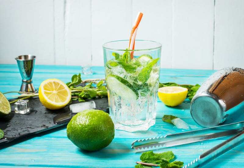 Mojito coctail med limefrukt och mintkaramellen i highballexponeringsglas på en blå wood tabell Drinkdanandehjälpmedel och ingred royaltyfri fotografi Mojito coctail med limefrukt och mintkaramellen i highballexponeringsglas på en blå wood tabell Drinkdanandehjälpmedel och ingred royaltyfri fotografi