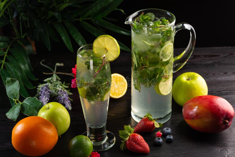 Mojito lemonad i en tillbringare och ett exponeringsglas och frukter på en mörk träbakgrund royaltyfria bilder Mojito lemonad i en tillbringare och ett exponeringsglas och frukter på en mörk träbakgrund royaltyfria bilder