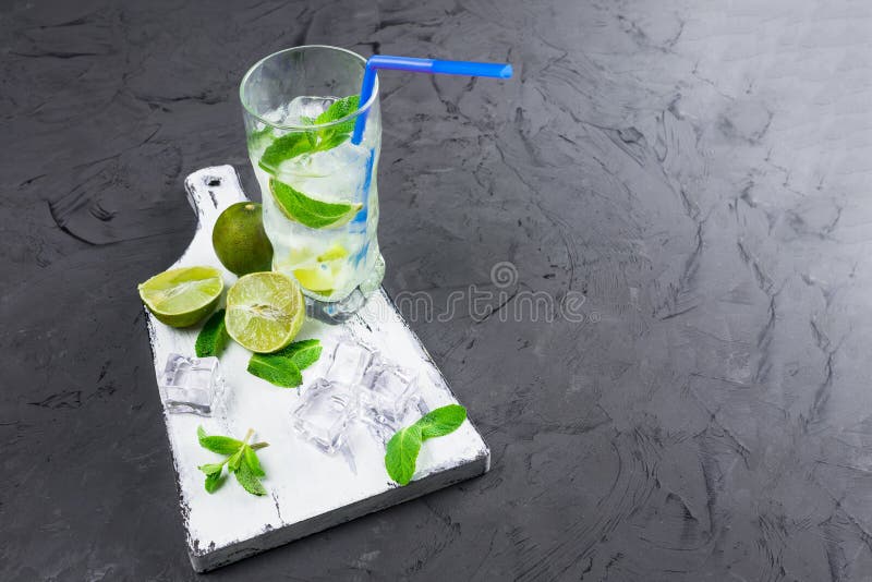 Mojito nos vidros, ao lado do cal e da hortelã na placa de corte Copie o espaço fotografia de stock Mojito nos vidros, ao lado do cal e da hortelã na placa de corte Copie o espaço fotografia de stock
