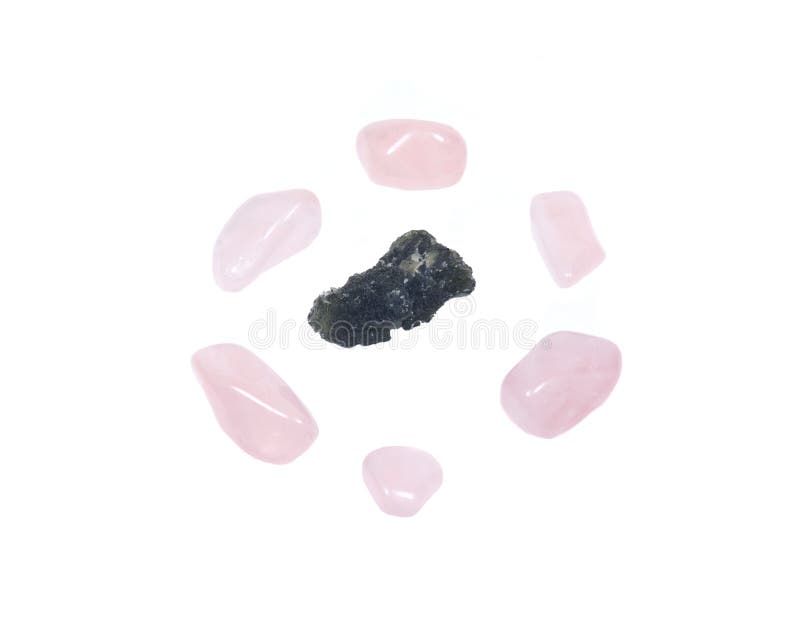 Moldavite - form of tektite found along the banks of the river Moldau in Czech republic, isolated on white background, surrounded by tumbled rose quartz pieces. Moldavite - form of tektite found along the banks of the river Moldau in Czech republic, isolated on white background, surrounded by tumbled rose quartz pieces