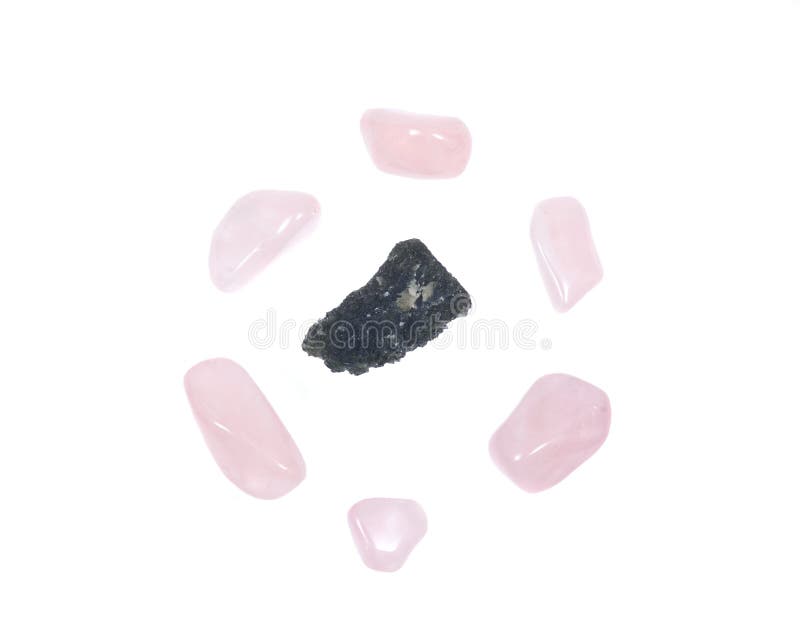 Moldavite - form of tektite found along the banks of the river Moldau in Czech republic, isolated on white background, surrounded by tumbled rose quartz pieces. Moldavite - form of tektite found along the banks of the river Moldau in Czech republic, isolated on white background, surrounded by tumbled rose quartz pieces