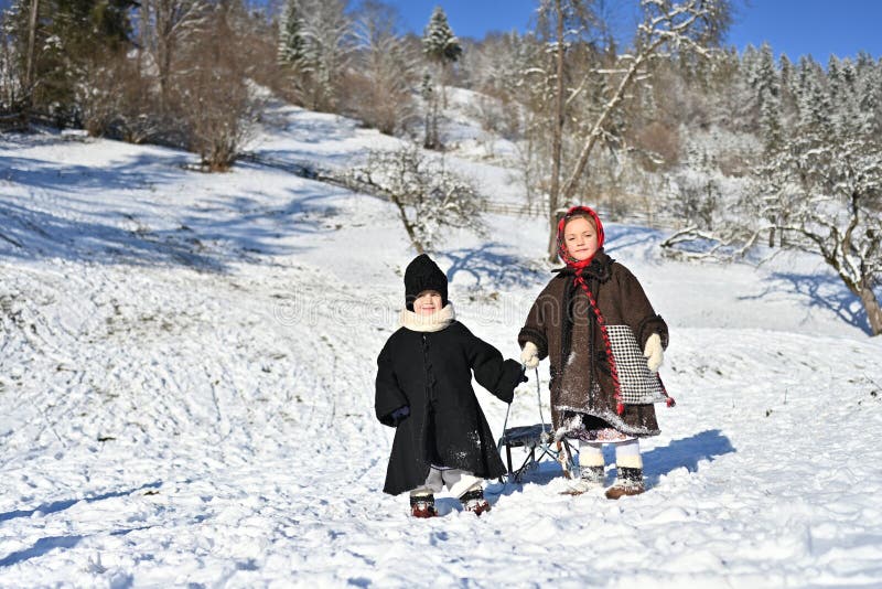 Moldovita, Romania, November 30th, 2018: Children wearing traditional playing with snow and sleigh on the sleighroad in Bucovina