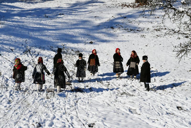 Moldovita, Romania, November 30th, 2018: Children wearing traditional playing with snow and sleigh on the sleighroad in Bucovina