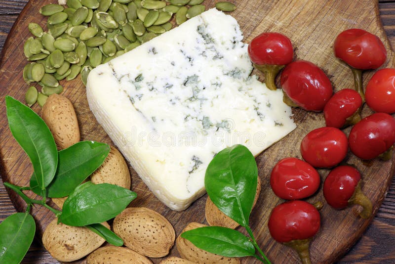 Moldy Cheese with Almonds, Pumpkin Seeds and Cherry Pepper on a Cutting Board. Blue Cheese Stock