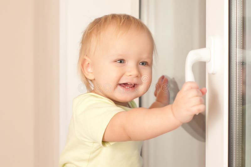 Adorable toddler girl holding window knob. Adorable toddler girl holding window knob