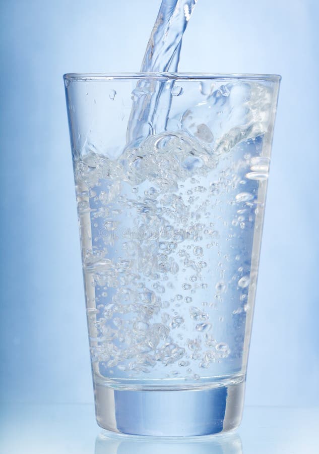 Water pouring into glass on blue background. Water pouring into glass on blue background