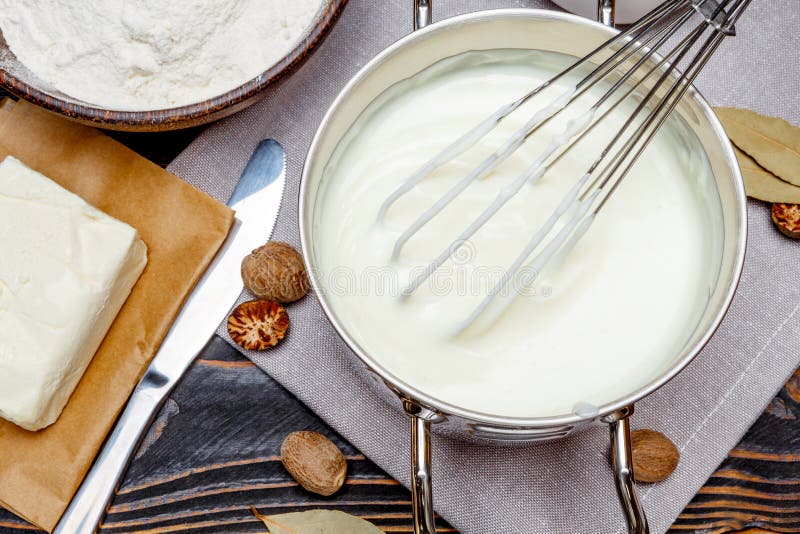 Preparation of bechamel sauce in a pan and ingredients on the wooden table. Preparation of bechamel sauce in a pan and ingredients on the wooden table