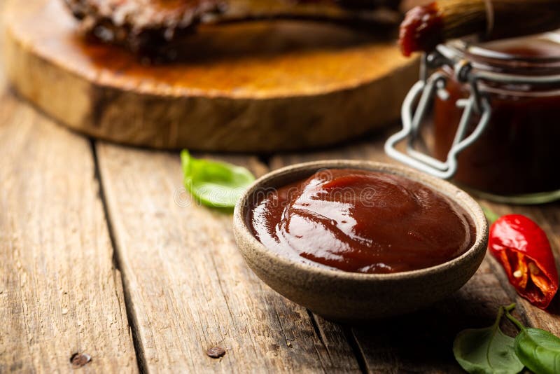 Barbecue sauce in a saucer with basting brush over rustic barn wood table with copy space. Barbecue sauce in a saucer with basting brush over rustic barn wood table with copy space.