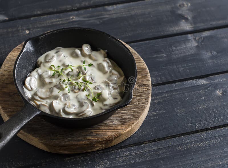 Creamy mushroom sauce in a pan on a wooden rustic board on a dark background. Creamy mushroom sauce in a pan on a wooden rustic board on a dark background