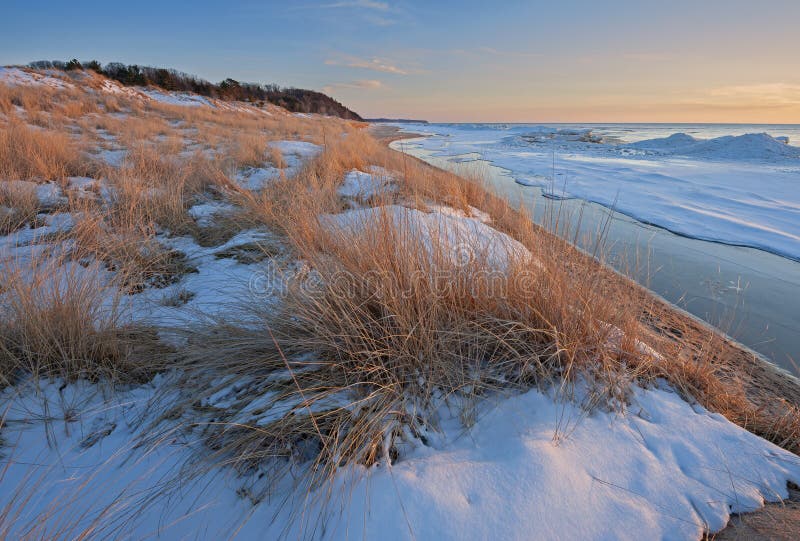 Winter landscape of beach grasses and iced shoreline of Lake Michigan near sunset, Saugatuck Dunes State Park, Michigan, USA. Winter landscape of beach grasses and iced shoreline of Lake Michigan near sunset, Saugatuck Dunes State Park, Michigan, USA