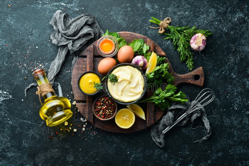 Cooking mayonnaise sauce. Oil, mustard and eggs. Culinary black stone background. Top view. Cooking mayonnaise sauce. Oil, mustard and eggs. Culinary black stone background. Top view