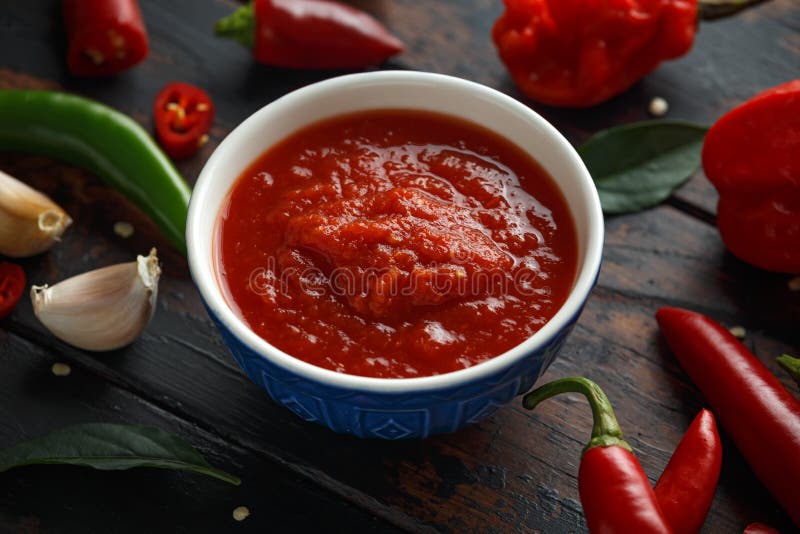 Molho de pimentão doce quente picante com mistura de pimenta, de alho e de tomates no fundo de madeira rústico imagens de stock royalty free Molho de pimentão doce quente picante com mistura de pimenta, de alho e de tomates no fundo de madeira rústico imagens de stock royalty free