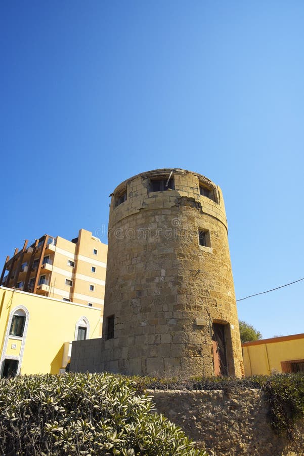 Molino de viento viejo en Ellie Beach que es la playa más cercana a Rhodes Town y es popular entre los locals y los turistas igua fotos de archivo libres de regalías Molino de viento viejo en Ellie Beach que es la playa más cercana a Rhodes Town y es popular entre los locals y los turistas igua fotos de archivo libres de regalías