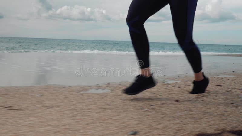 Mollige junge weibliche Beine Rütteln auf See. Fitness- und Sportkonzept. Frau läuft auf nassen Sand zu tropischem Strand. laufend