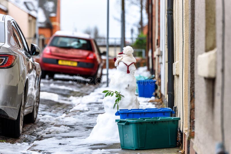 Molnig sikt för vinterdag av den hemlagade snögubben på den typiska brittiska vägvandringsledet bredvid tomma återvinningfackaska fotografering för bildbyråer Molnig sikt för vinterdag av den hemlagade snögubben på den typiska brittiska vägvandringsledet bredvid tomma återvinningfackaska fotografering för bildbyråer