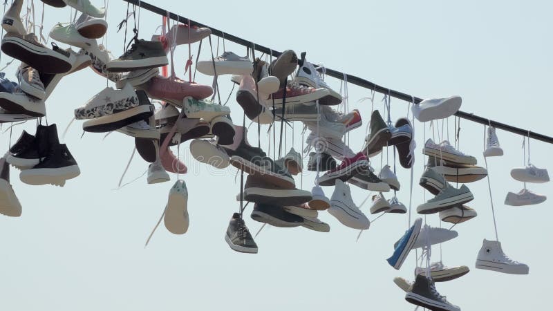 Molte delle scarpe da tennis d'avanguardia stanno appendendo sulle corde all'aperto, inclinazione sulla vista contro il cielo