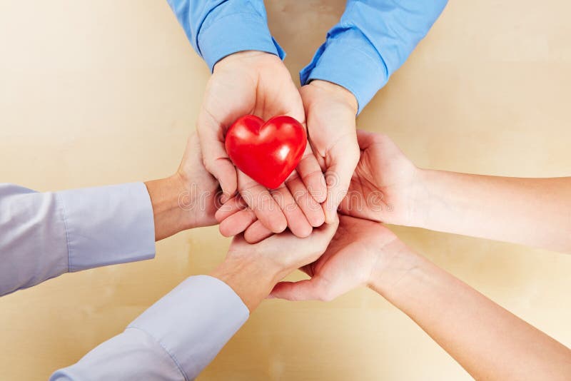 Molte mani che tengono un cuore rosso fotografia stock libera da diritti Molte mani che tengono un cuore rosso fotografia stock libera da diritti