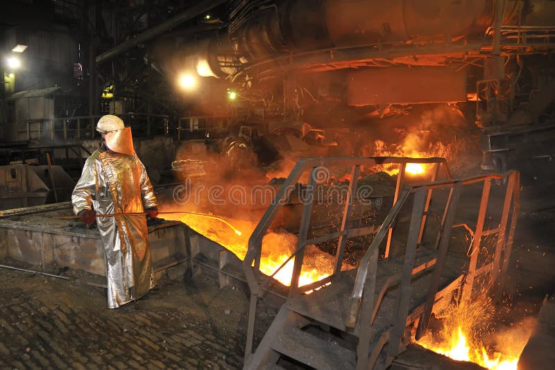 Fuso caldo di acciaio e di versamento dell'operaio all'interno della fabbrica.