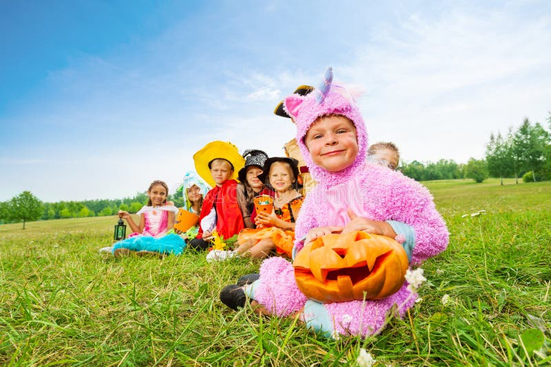 Molti costumi di usura dei bambini di Halloween si siedono nella fila lunga immagini stock Molti costumi di usura dei bambini di Halloween si siedono nella fila lunga immagini stock