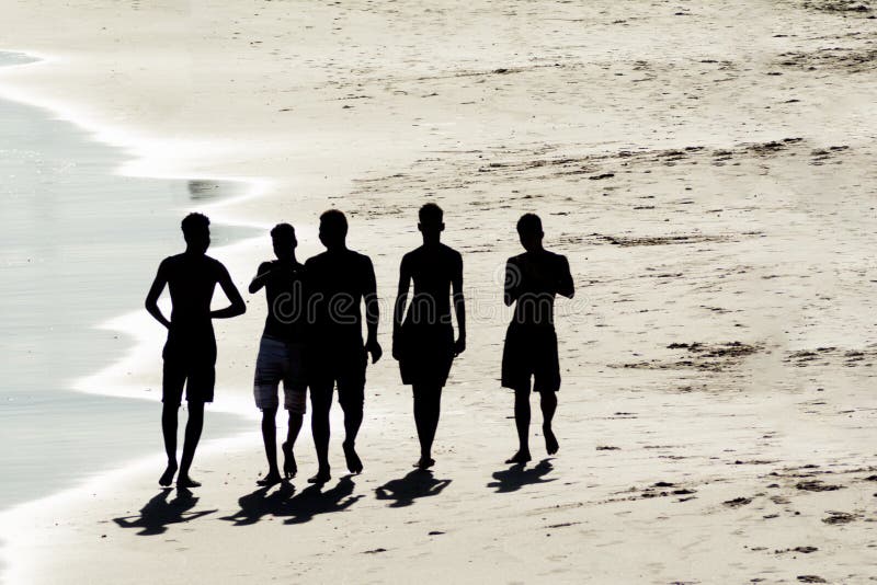 Molti giovani a silhouette in spiaggia giocano a divertirsi e fanno il bagno in mare fotografie stock