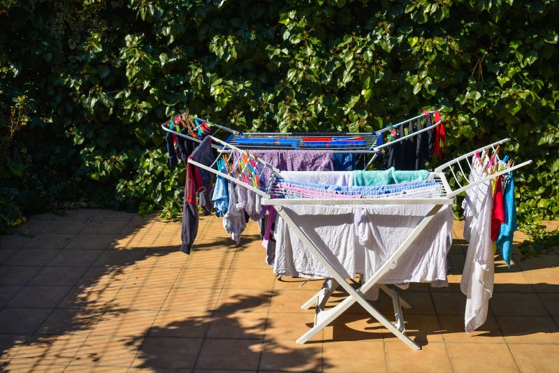 molti vestiti differenti che tengono nel lavare linea ad un giardino in un giorno soleggiato fotografia stock molti vestiti differenti che tengono nel lavare linea ad un giardino in un giorno soleggiato fotografia stock