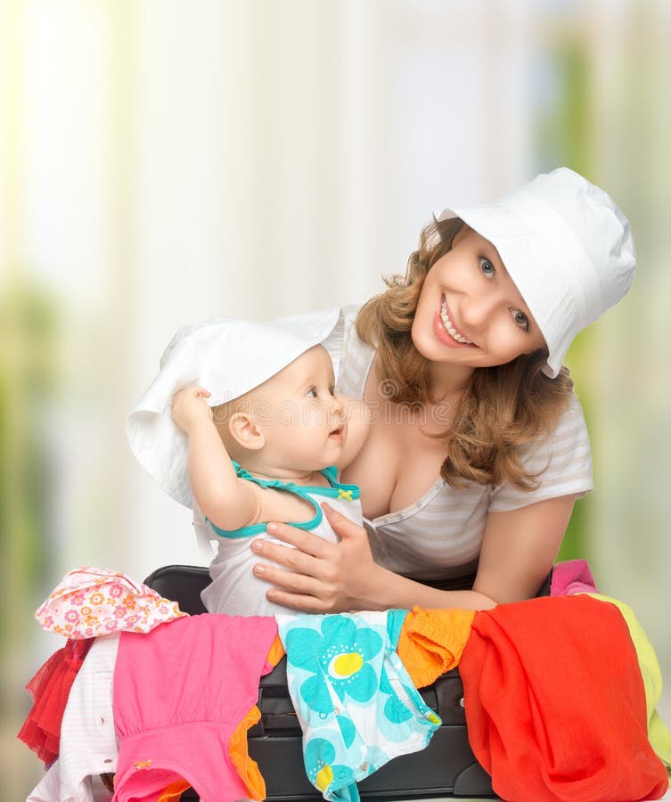Mom and baby girl with suitcase and clothes ready for traveling