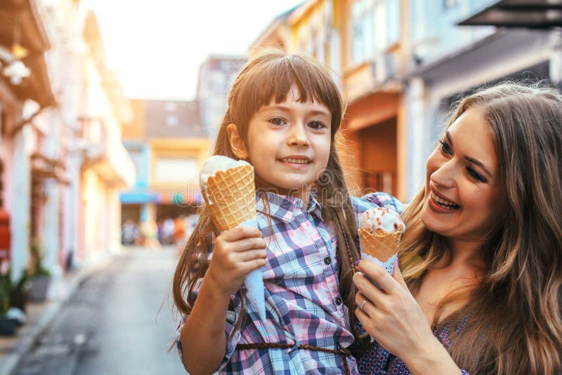 Mom with child eating ice cream in city street. Cute, person.