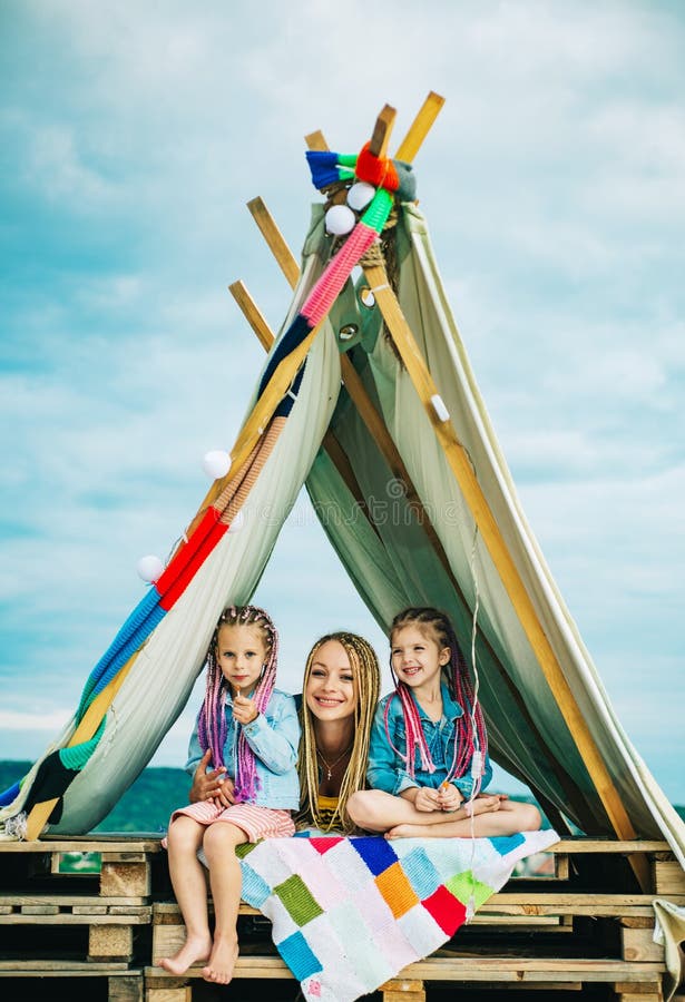 Mom with children girl in tent. Summer outdoor. Family playing together. Happy mother laughing with kids, camping