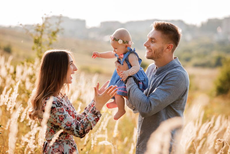 Mom, dad and little girl having fun outdoors in the grass on summer day. mother`s, father`s and baby`s day. Happy family for a