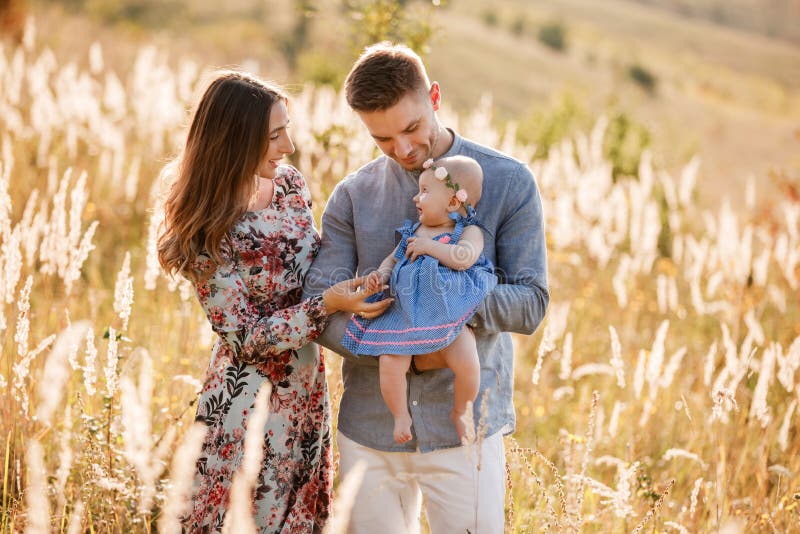 Mom, dad and little girl having fun outdoors in the grass on summer day. mother`s, father`s and baby`s day. Happy family