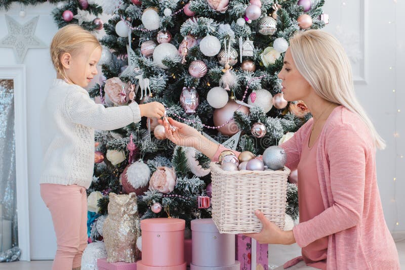 Mom and daughter decorate the Christmas tree Stock Photo by