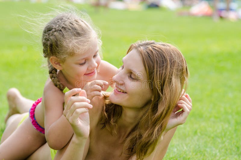 Mom And Daughter Having Fun Lying On A Green Lawn In The Summer Stock
