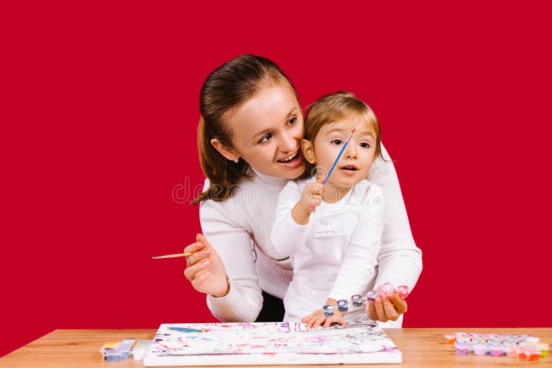 Mom and daughter paint a picture by numbers at isolated houses during a pandemic. Family time. Red background.