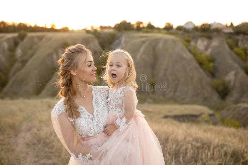 Mom with daughter in pink fairy-tale dresses walk in nature. Little princess childhood royalty free stock photo Mom with daughter in pink fairy-tale dresses walk in nature. Little princess childhood royalty free stock photo