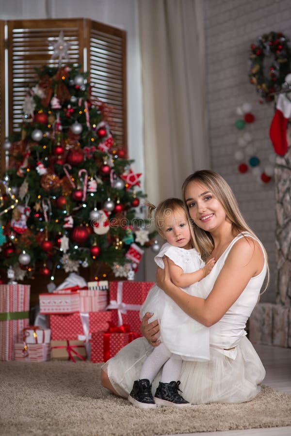 Mom and daughter are sitting around the Christmas tree stock photo Mom and daughter are sitting around the Christmas tree stock photo