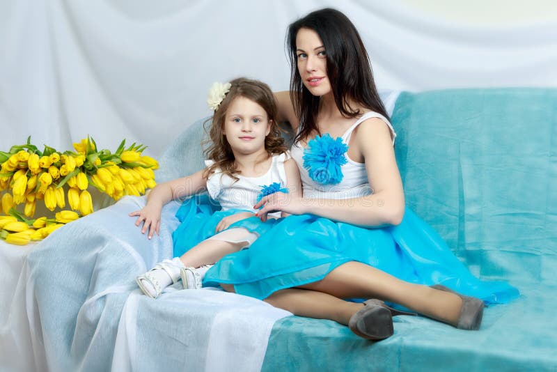 Mom and Daughter on the Sofa with a Bouquet of Flowers. Stock Photo ...