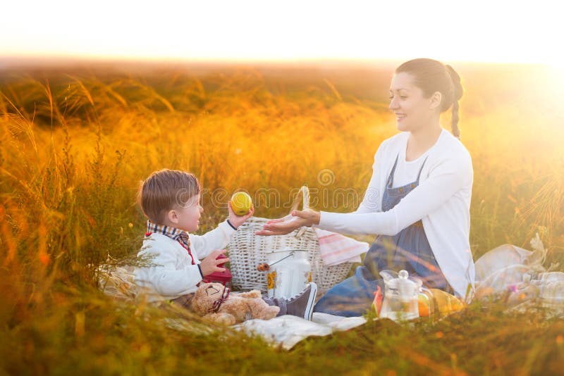 Mom feeds her son on a picnic. Mother and young son in sunny fall day. Happy family and healthy eating concept stock images Mom feeds her son on a picnic. Mother and young son in sunny fall day. Happy family and healthy eating concept stock images