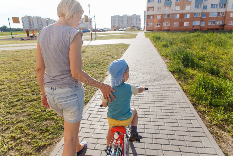 Mom Helps Son To Ride A Bicycle Stock Image
