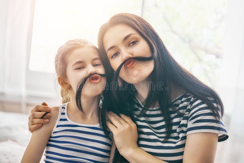 mom and her child daughter are playing having fun together beautiful funny girl mother have mustache family holidays togetherness