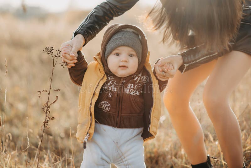 Mom holds her baby boy by the hands for a walk. Baby`s first steps stock images Mom holds her baby boy by the hands for a walk. Baby`s first steps stock images