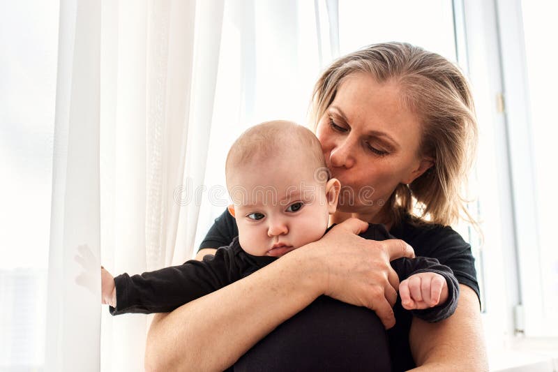 Mom Hugs and Kisses Her Little Child in a Bright Child S Room. Mom ...