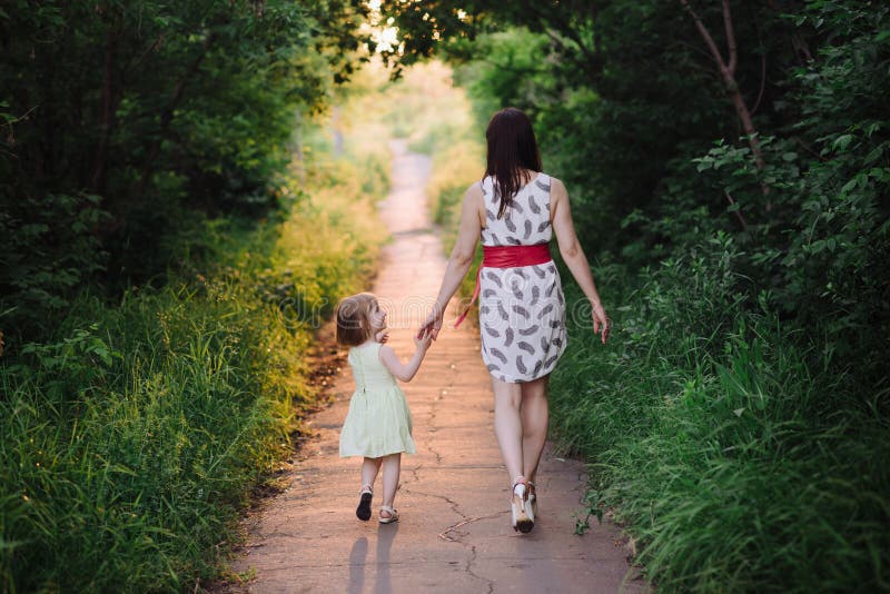 Дочки пошли в маму. Девочка идет за руку с мамой. Девочка гуляет с мамой. Мама с дочкой идут за руку. Девушка с дочкой идет.