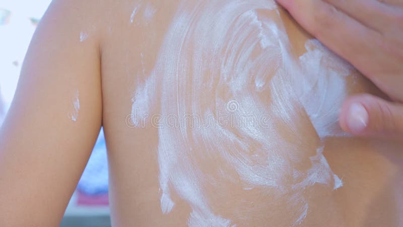 Mom smear sunblock cream on her daughter shoulder on the beach.