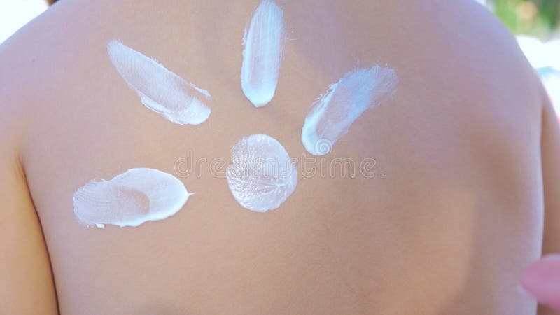 Mom smear sunblock cream on her daughter shoulder on the beach.