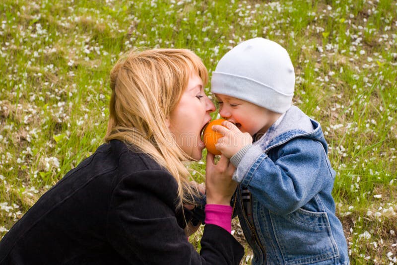 Mamma e figlio giocare con un'arancia su un prato.