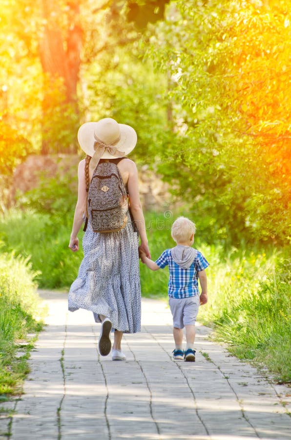 Mom and son walking along the road in the park. Back view stock photos Mom and son walking along the road in the park. Back view stock photos
